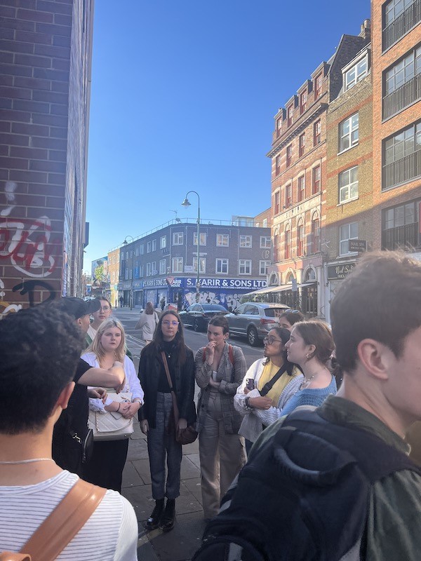 Students gather in street listening to tour guide speak