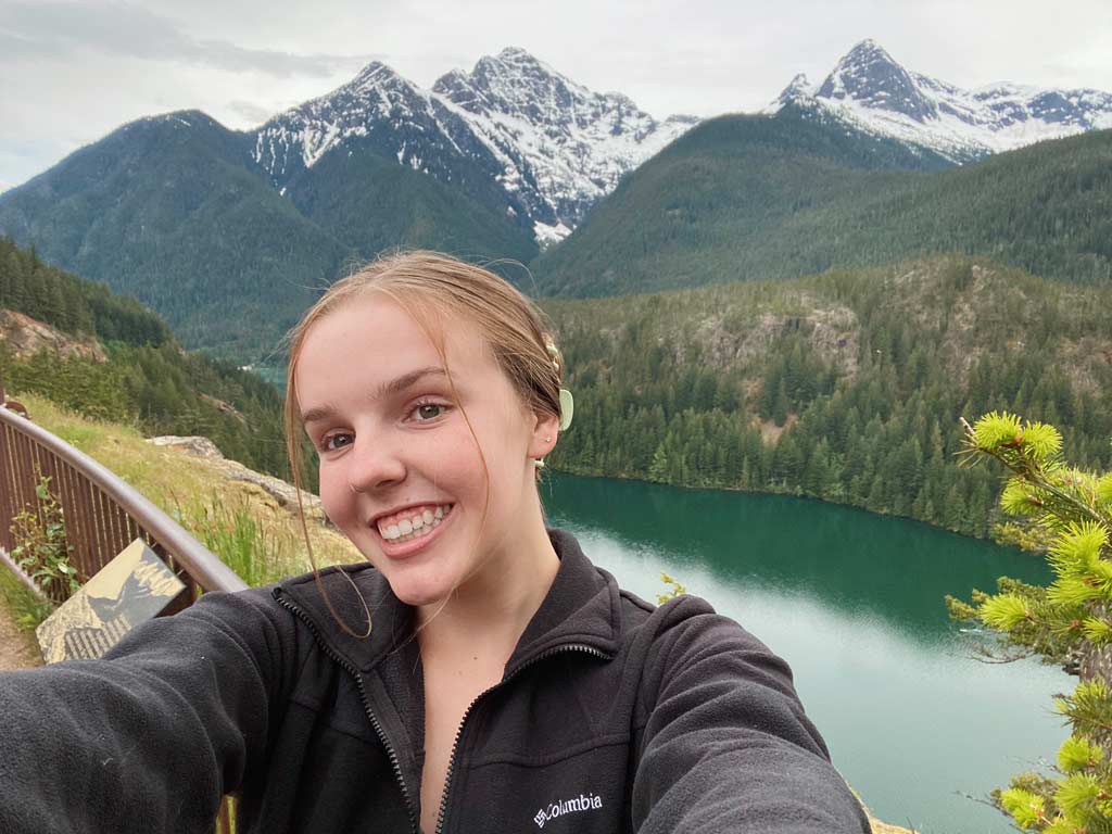 student smiling with mountains in background