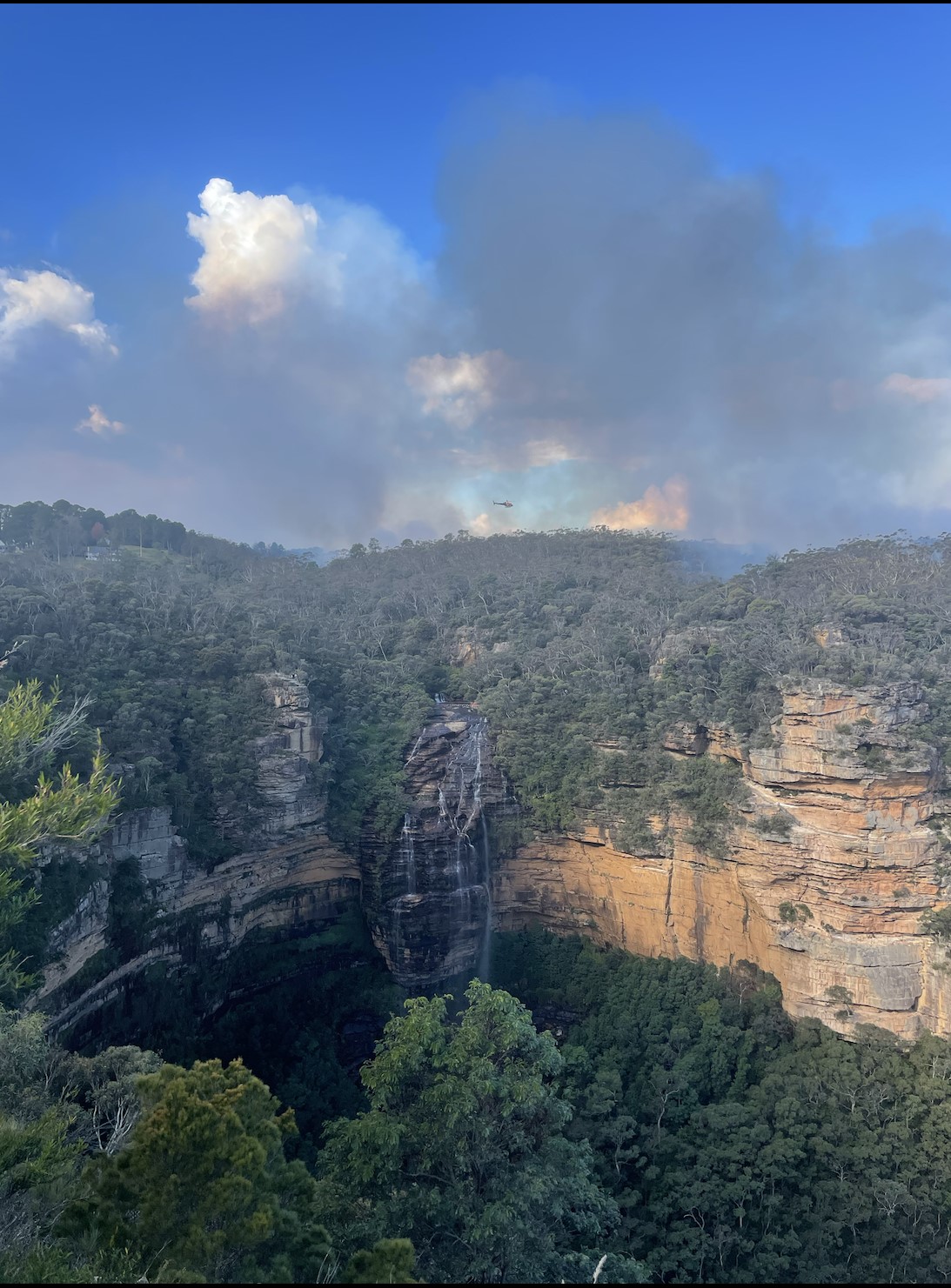 Smoke arising from a controlled burn area around a mountain.