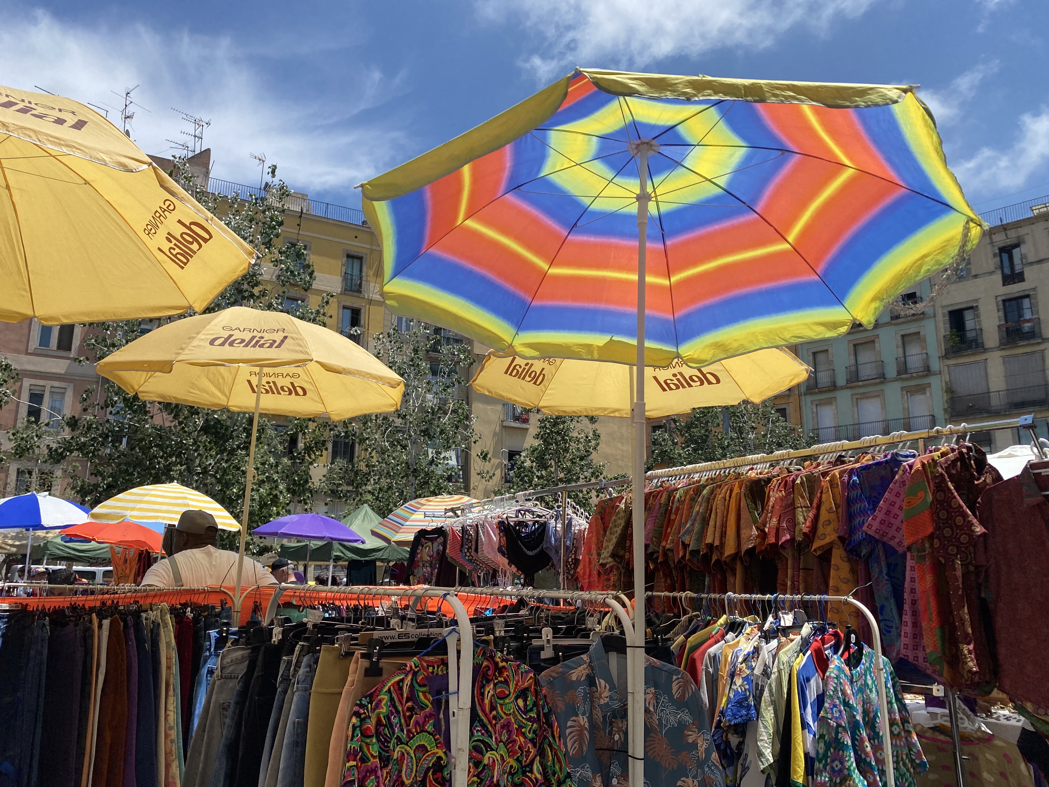 Racks of clothes under umbrellas outdoors