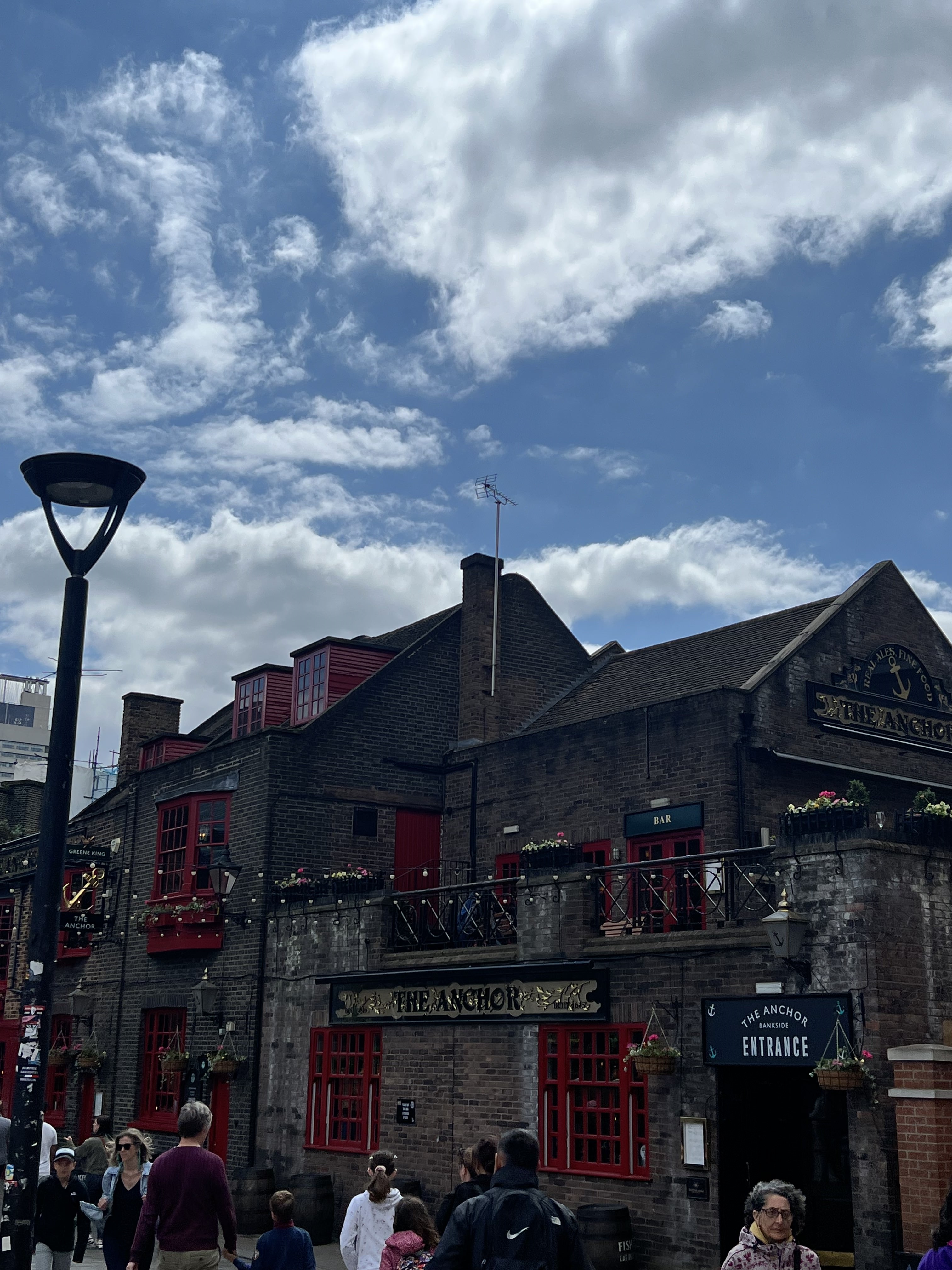 A stream of people walking outside a pub building.