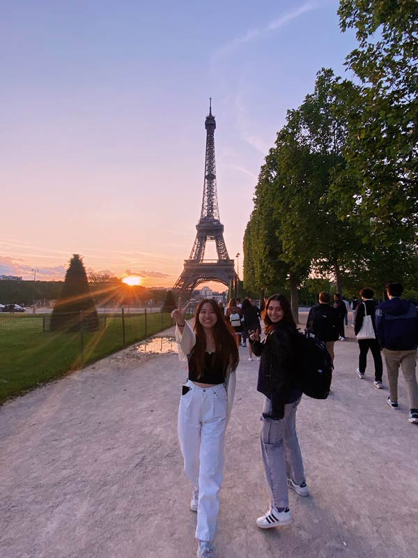 2 CEA CAPA students pose in front of Eiffel Tower at sunset