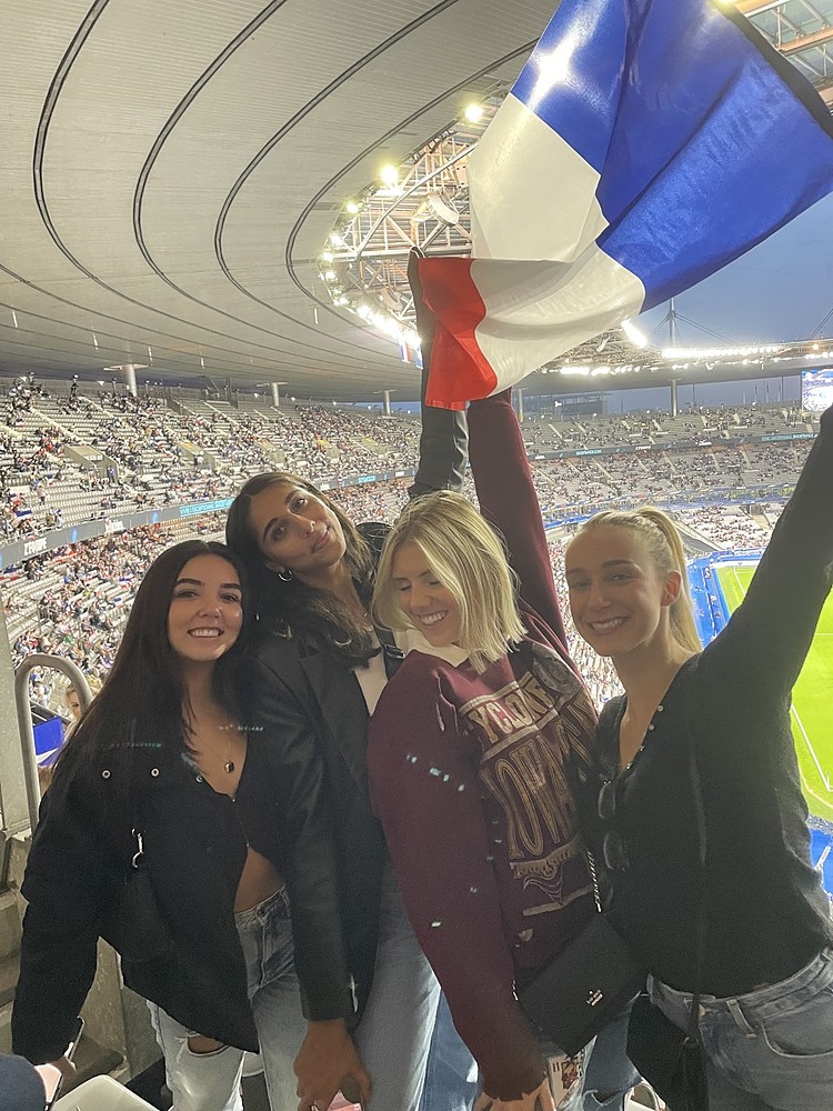 Four students wave French flag at soccer stadium in France
