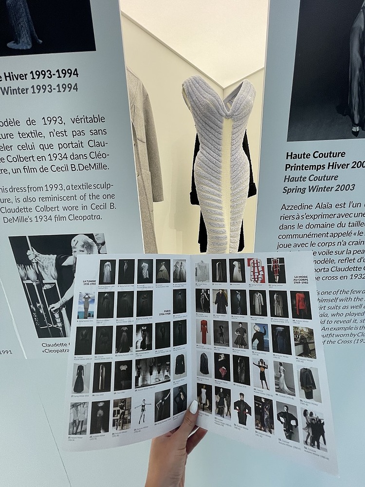 Student holding a book filled with fashion inspiration and imagery at an Exhibit