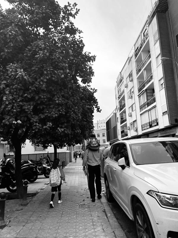 Black and white photo of father walking children to school.