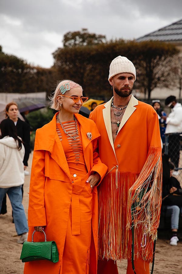 A couple wearing orange in Jardin des Tuileries at Paris Fashion Week 2022