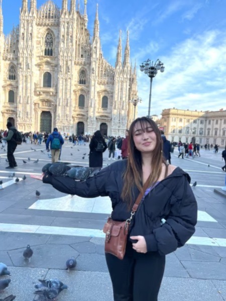 Student lifting hand in front of cathedral