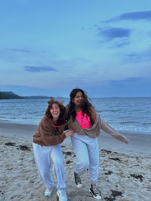Two students smiling happily on the beach.