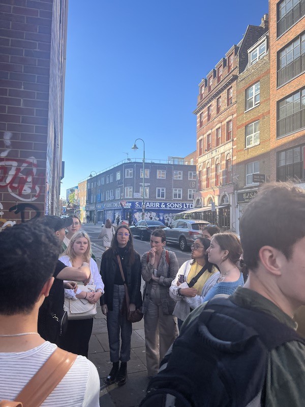 Students gather in street listening to tour guide speak