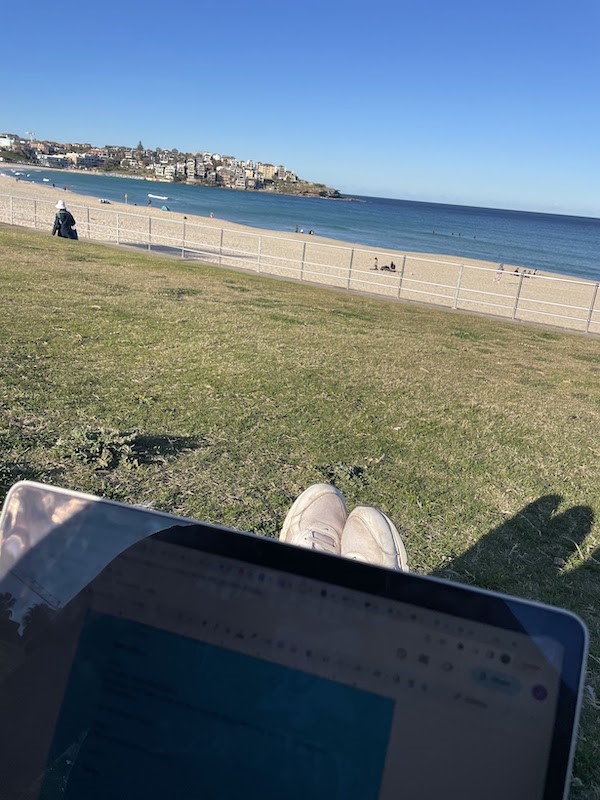 A person using their laptop with a view of Bondi Beach