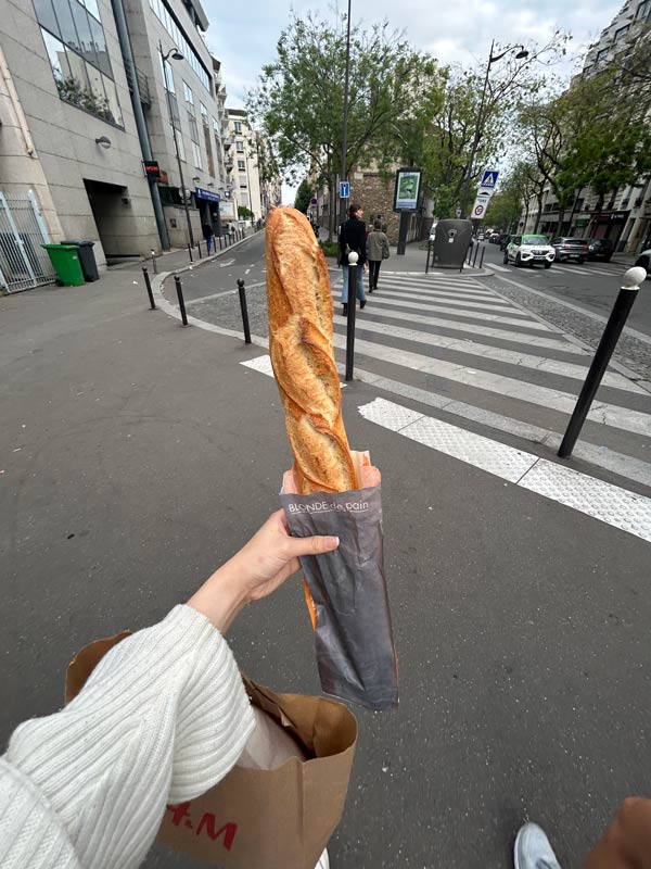 Student holding a fresh baguette in the streets of Paris